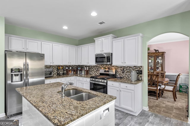 226 Creek View Ln, Acworth, GA 30102 - kitchen featuring appliances with stainless steel finishes, arched walkways, white cabinets, light stone countertops, and tasteful backsplash