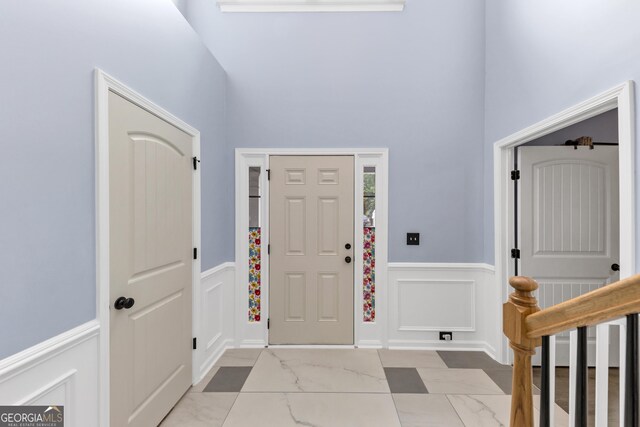 226 Creek View Ln, Acworth, GA 30102 - entrance foyer featuring marble look tiles, wainscoting, a decorative wall, and a high ceiling
