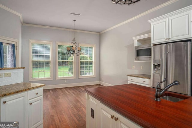 1811 Traditions Way, Jefferson, GA 30549 - kitchen featuring appliances with stainless steel finishes, a chandelier, wood finished floors, white cabinetry, and crown molding