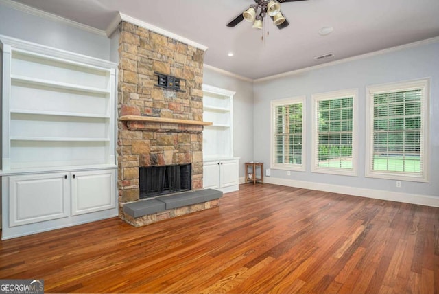 1811 Traditions Way, Jefferson, GA 30549 - unfurnished living room featuring a stone fireplace, ornamental molding, wood finished floors, a ceiling fan, and built in features