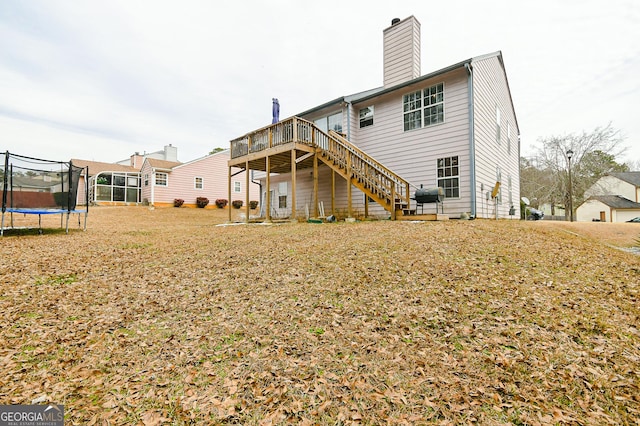 3251 Hunters Crossing Pt, Lithonia, GA 30038 - back of property featuring a trampoline, a deck, stairs, and a chimney