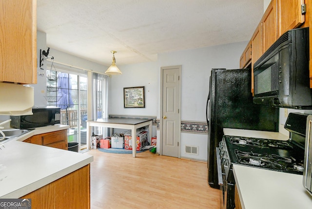 3251 Hunters Crossing Pt, Lithonia, GA 30038 - kitchen with range with gas cooktop, black microwave, and brown cabinetry
