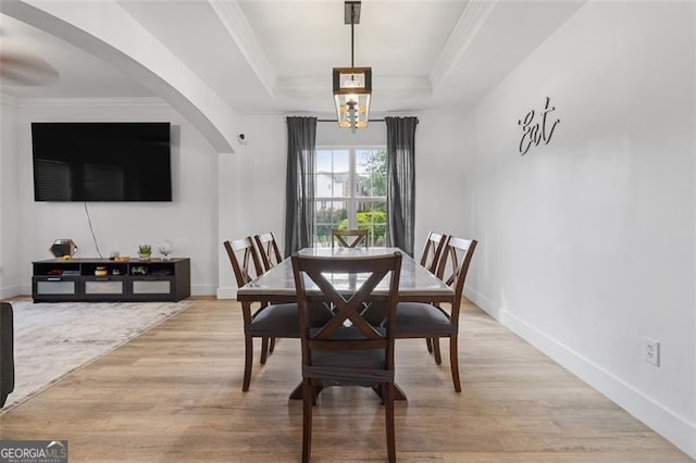 1657 Bradmere Ln, Lithia Springs, GA 30122 - dining space with light wood-style flooring, a raised ceiling, ornamental molding, arched walkways, and a chandelier