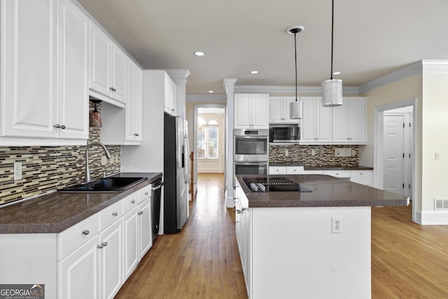 3450 Merganser Ln, Alpharetta, GA 30022 - kitchen featuring appliances with stainless steel finishes, a center island, crown molding, light wood-style flooring, and backsplash