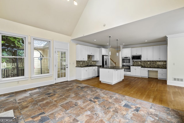 3450 Merganser Ln, Alpharetta, GA 30022 - kitchen with stainless steel appliances, dark countertops, decorative backsplash, white cabinetry, and high vaulted ceiling
