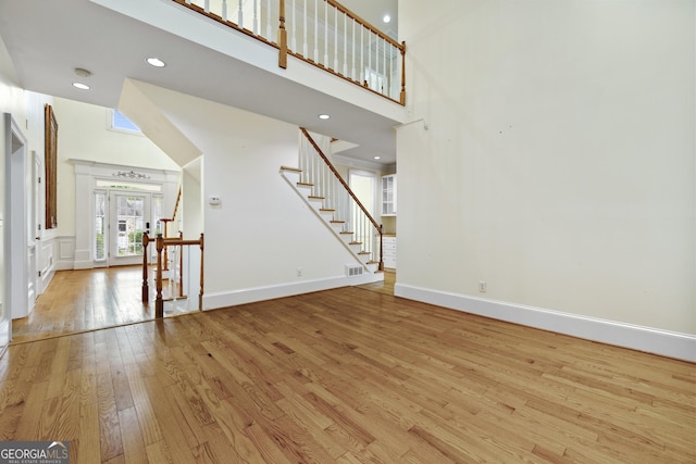 3450 Merganser Ln, Alpharetta, GA 30022 - unfurnished living room with wood-type flooring, stairs, a towering ceiling, recessed lighting, and french doors