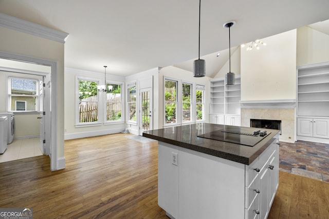 3450 Merganser Ln, Alpharetta, GA 30022 - kitchen with black electric cooktop, a chandelier, washer and clothes dryer, a tiled fireplace, and a kitchen island