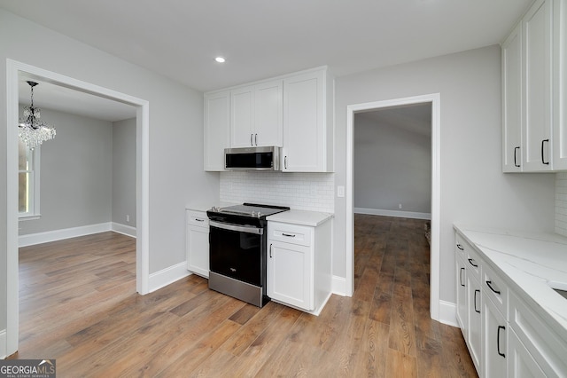 858 Pates Creek Rd, Stockbridge, GA 30281 - kitchen featuring appliances with stainless steel finishes, backsplash, a chandelier, white cabinetry, and light wood-style floors