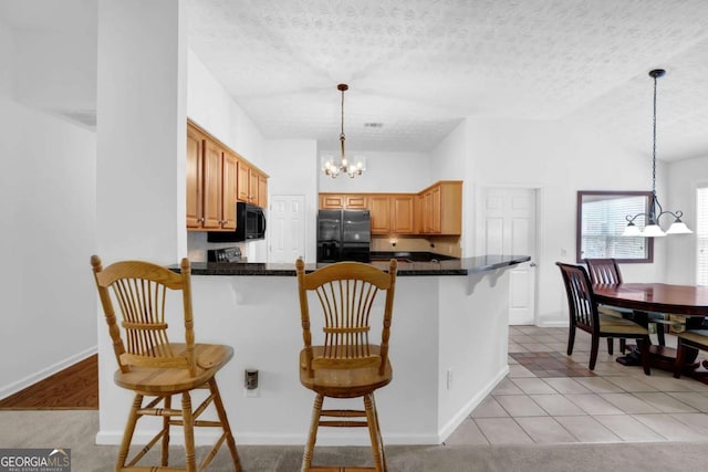 5565 Ashmoore Ct, Flowery Branch, GA 30542 - kitchen with a chandelier, black appliances, a peninsula, a kitchen bar, and dark countertops