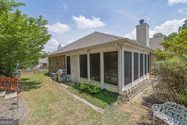 5565 Ashmoore Ct, Flowery Branch, GA 30542 - back of house with a sunroom, a chimney, and a shingled roof