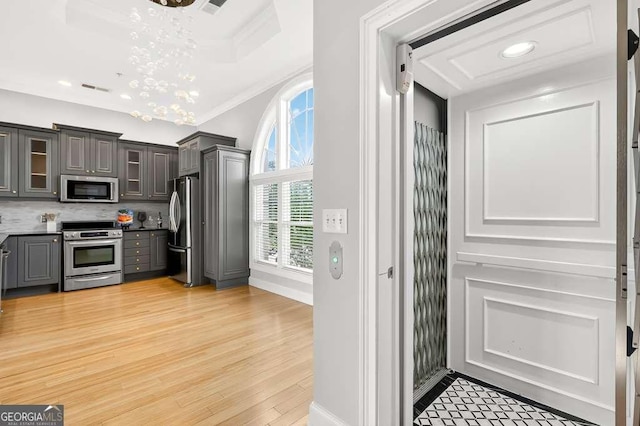 3541 Roswell Rd NE Unit 21, Atlanta, GA 30305 - kitchen featuring stainless steel appliances, gray cabinets, a chandelier, glass insert cabinets, and light wood finished floors