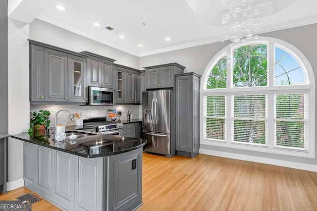 3541 Roswell Rd NE Unit 21, Atlanta, GA 30305 - kitchen featuring appliances with stainless steel finishes, gray cabinetry, a peninsula, dark stone countertops, and glass insert cabinets