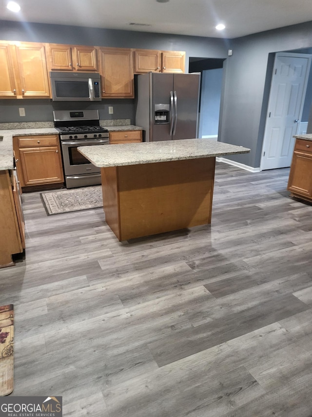 1962 Bridgestone Cir, Conyers, GA 30012 - kitchen featuring stainless steel appliances, recessed lighting, a center island, light stone countertops, and wood finished floors