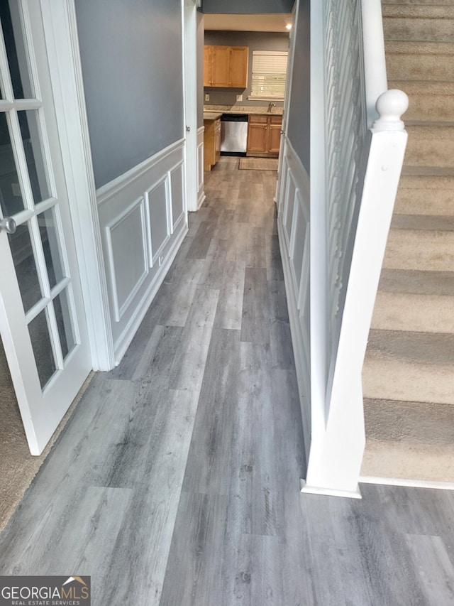 1962 Bridgestone Cir, Conyers, GA 30012 - hallway featuring stairway, a decorative wall, a wainscoted wall, and wood finished floors
