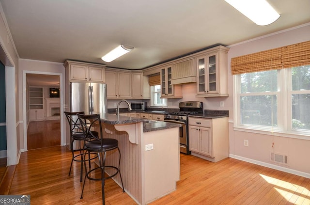 4714 Marc Ct SW, Lilburn, GA 30047 - kitchen with stainless steel appliances, light wood-type flooring, a kitchen bar, crown molding, and an island with sink