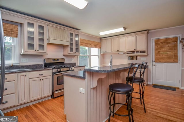 4714 Marc Ct SW, Lilburn, GA 30047 - kitchen featuring stainless steel range with gas cooktop, light wood finished floors, a breakfast bar area, a kitchen island, and glass insert cabinets