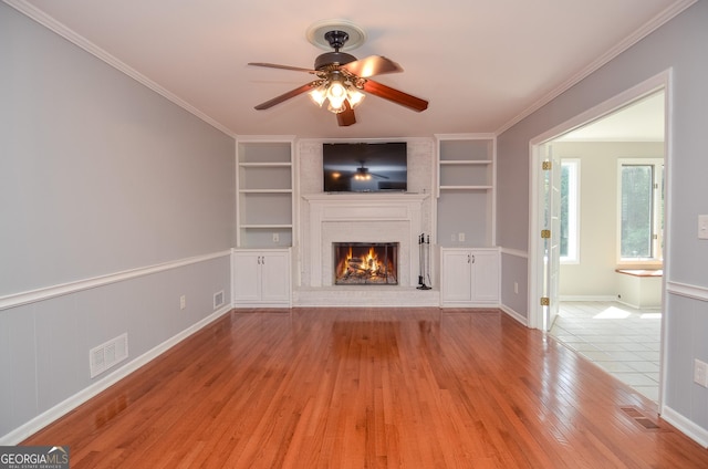 4714 Marc Ct SW, Lilburn, GA 30047 - unfurnished living room featuring built in shelves, a brick fireplace, light wood-style flooring, ceiling fan, and ornamental molding