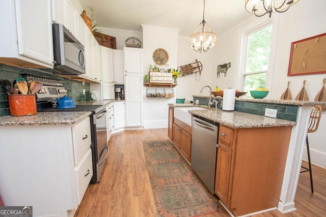 202 E Oak St, Luthersville, GA 30251 - kitchen featuring stainless steel appliances, a chandelier, ornamental molding, light wood-type flooring, and backsplash