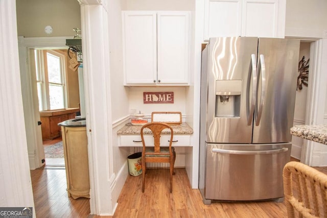 202 E Oak St, Luthersville, GA 30251 - kitchen with stainless steel fridge, light wood finished floors, white cabinetry, and light stone counters