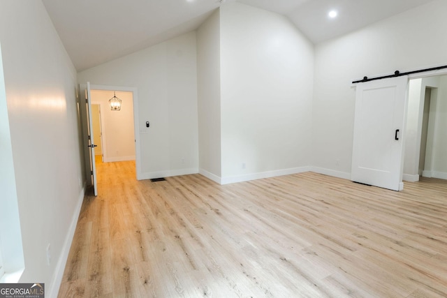 206 2nd St, Gainesville, GA 30504 - empty room featuring a barn door, light wood-style flooring, and high vaulted ceiling