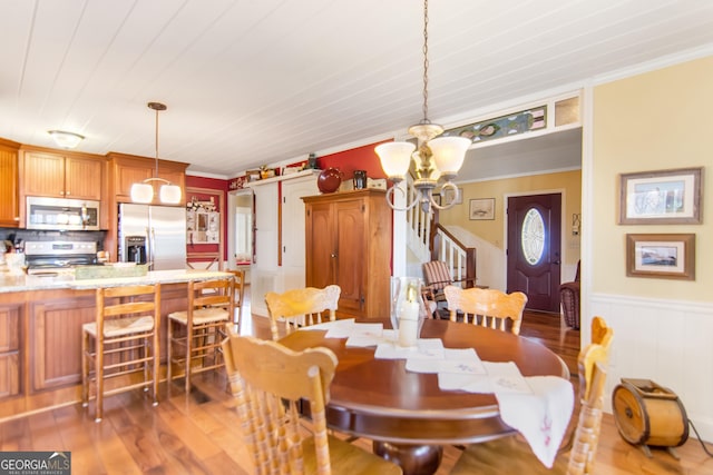 705 Laurel Ridge Dr, Ellijay, GA 30536 - dining room featuring a chandelier, crown molding, a wainscoted wall, light wood finished floors, and a decorative wall