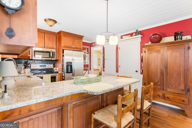705 Laurel Ridge Dr, Ellijay, GA 30536 - kitchen featuring appliances with stainless steel finishes, a peninsula, wood finished floors, brown cabinetry, and decorative backsplash