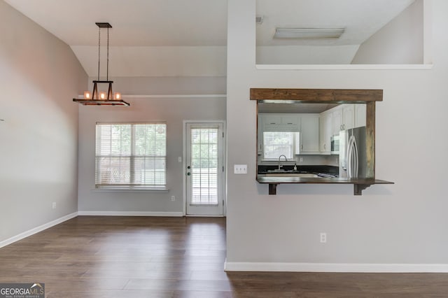 926 Masters Dr, Monroe, GA 30655 - kitchen with dark countertops, vaulted ceiling, stainless steel appliances, dark wood-style flooring, and a breakfast bar area