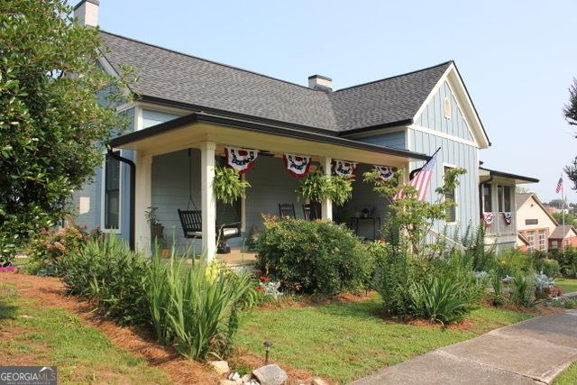 5880 Mulberry St, Austell, GA 30168 - view of front of house with a chimney, a porch, roof with shingles, and board and batten siding