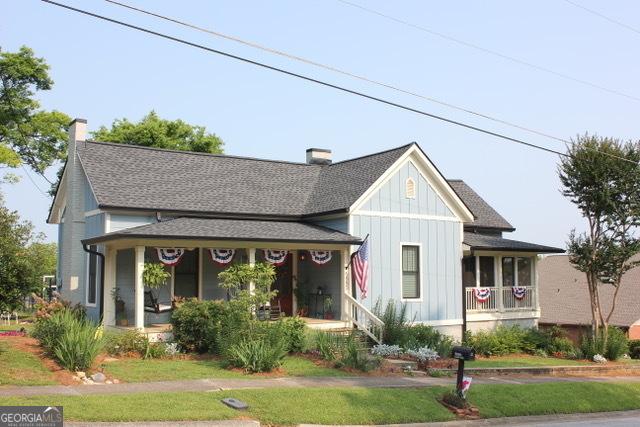 5880 Mulberry St, Austell, GA 30168 - view of front facade with a porch, board and batten siding, a chimney, and roof with shingles