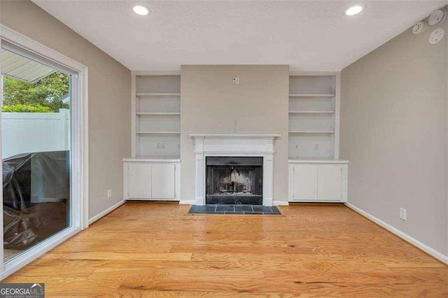 122 S Island Square Dr, Saint Simons, GA 31522 - unfurnished living room with a fireplace with flush hearth, light wood-style floors, a textured ceiling, recessed lighting, and built in shelves