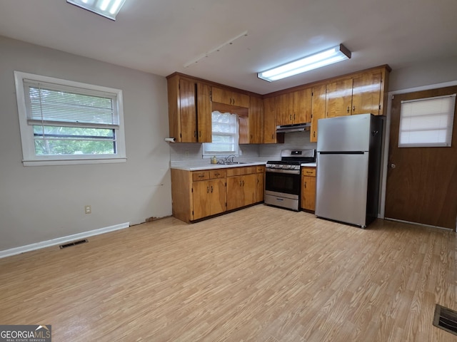 104 Denham St, Thomaston, GA 30286 - kitchen featuring stainless steel appliances, under cabinet range hood, light countertops, light wood-type flooring, and brown cabinetry