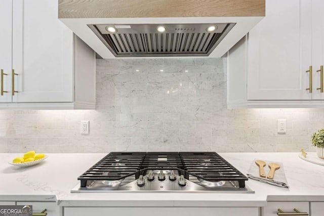 2243 Cain Cir, Dacula, GA 30019 - kitchen with range hood, stainless steel gas cooktop, white cabinetry, and tasteful backsplash