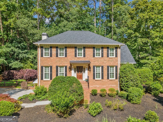 2502 Tritt Springs Trce NE, Marietta, GA 30062 - colonial home featuring a chimney, brick siding, a shingled roof, and view of scattered trees