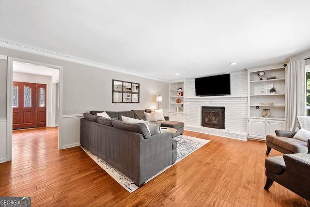 2502 Tritt Springs Trce NE, Marietta, GA 30062 - living room with light wood-type flooring, a brick fireplace, crown molding, built in shelves, and a wainscoted wall
