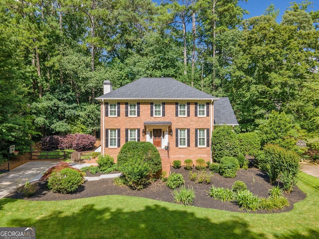2502 Tritt Springs Trce NE, Marietta, GA 30062 - colonial home featuring a chimney, brick siding, and view of wooded area
