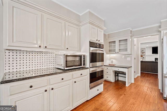 2502 Tritt Springs Trce NE, Marietta, GA 30062 - kitchen with stainless steel appliances, light wood-type flooring, ornamental molding, dark stone counters, and glass insert cabinets