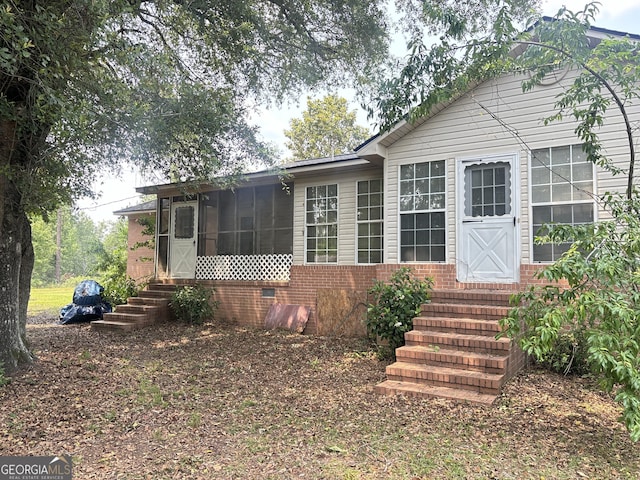 895 Ga Highway 57, Kite, GA 31049 - view of front of property with entry steps, a sunroom, and brick siding