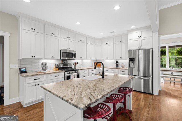 177 Garnett Point Dr, Carrollton, GA 30117 - kitchen featuring stainless steel appliances, dark wood-style flooring, ornamental molding, white cabinets, and backsplash