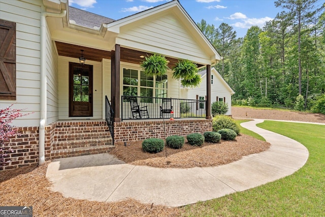177 Garnett Point Dr, Carrollton, GA 30117 - view of exterior entry with covered porch, roof with shingles, and a yard
