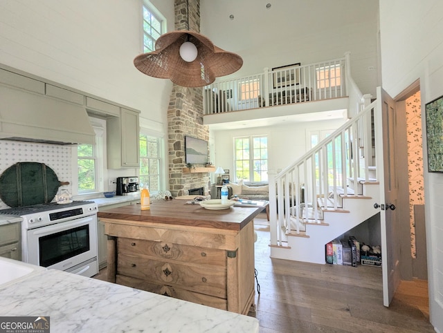 10540 Serenbe Ln, Chattahoochee Hills, GA 30268 - kitchen with white electric range, a towering ceiling, hardwood / wood-style floors, a stone fireplace, and healthy amount of natural light