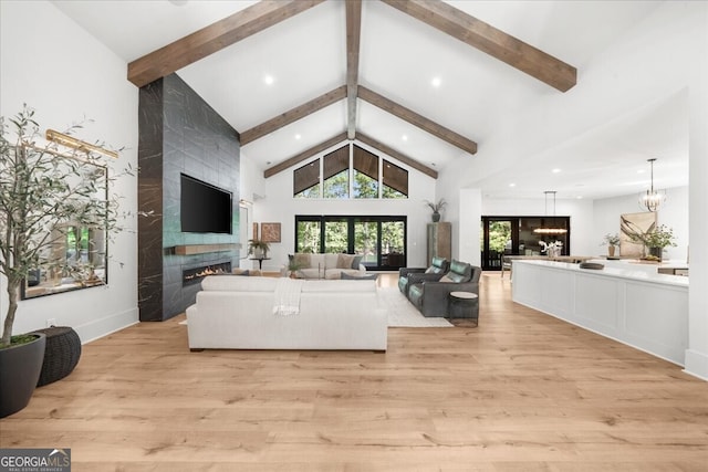 4451 Shellie Ln, Oakwood, GA 30566 - living room with beam ceiling, light wood-style flooring, a tiled fireplace, a chandelier, and high vaulted ceiling