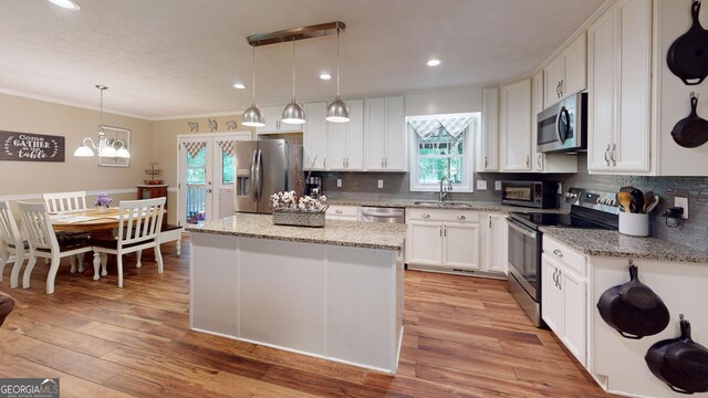 241 Lavern Ct, Winder, GA 30680 - kitchen featuring appliances with stainless steel finishes, crown molding, white cabinets, decorative backsplash, and a center island