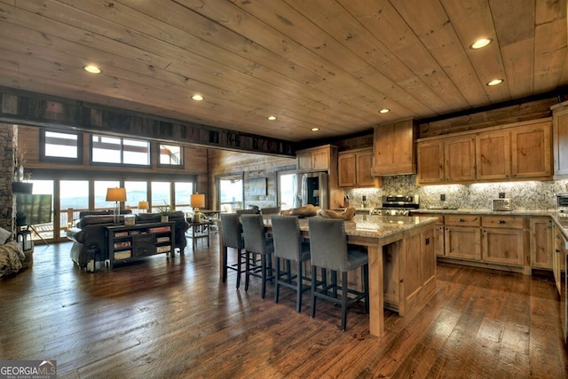 330 Serenity Ridge Ln, Mineral Bluff, GA 30559 - kitchen featuring appliances with stainless steel finishes, wood ceiling, a kitchen island, light stone counters, and a kitchen breakfast bar
