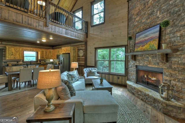 330 Serenity Ridge Ln, Mineral Bluff, GA 30559 - living room featuring a high ceiling, a stone fireplace, light wood-type flooring, and wooden walls