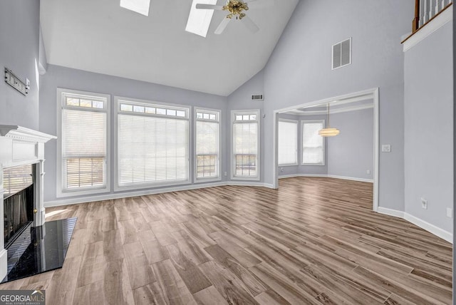 269 Legends Trce, Mcdonough, GA 30253 - unfurnished living room with high vaulted ceiling, ceiling fan, a fireplace, wood finished floors, and a skylight