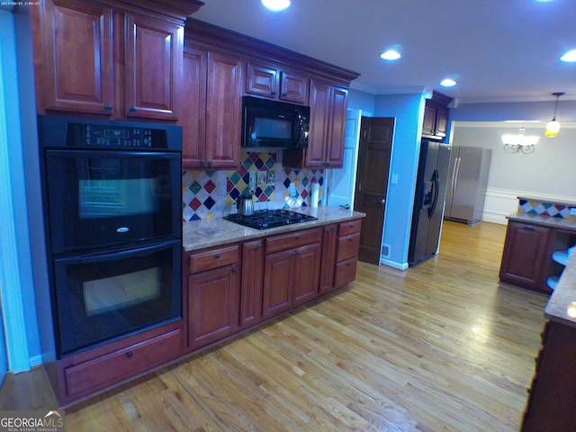5741 Wolf Laurel Ln SW, Lilburn, GA 30047 - kitchen with black appliances, a chandelier, light wood-style flooring, tasteful backsplash, and light stone countertops