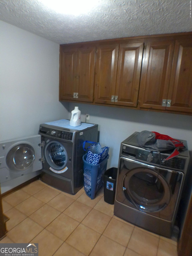5741 Wolf Laurel Ln SW, Lilburn, GA 30047 - laundry area with cabinet space, washer and clothes dryer, light tile patterned flooring, and a textured ceiling