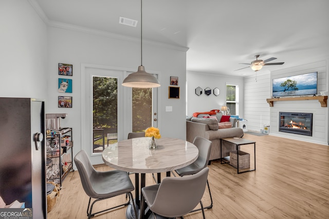 5615 Parkview Ln, Flowery Branch, GA 30542 - dining area featuring ornamental molding, light wood-style flooring, a glass covered fireplace, and ceiling fan