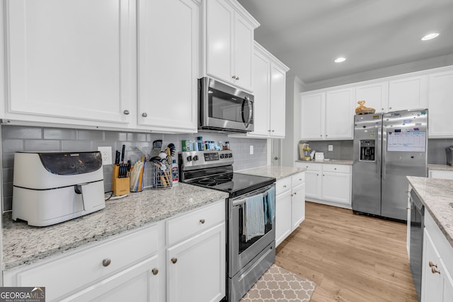 5615 Parkview Ln, Flowery Branch, GA 30542 - kitchen featuring appliances with stainless steel finishes, white cabinetry, backsplash, light wood-style floors, and recessed lighting