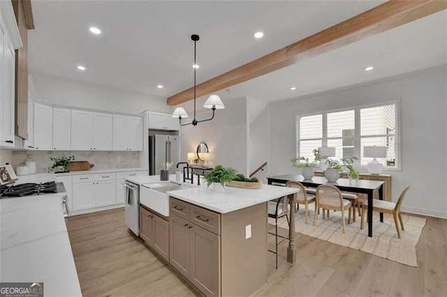 830 Gaston St SW, Atlanta, GA 30310 - kitchen with appliances with stainless steel finishes, beamed ceiling, light wood-style floors, white cabinets, and backsplash
